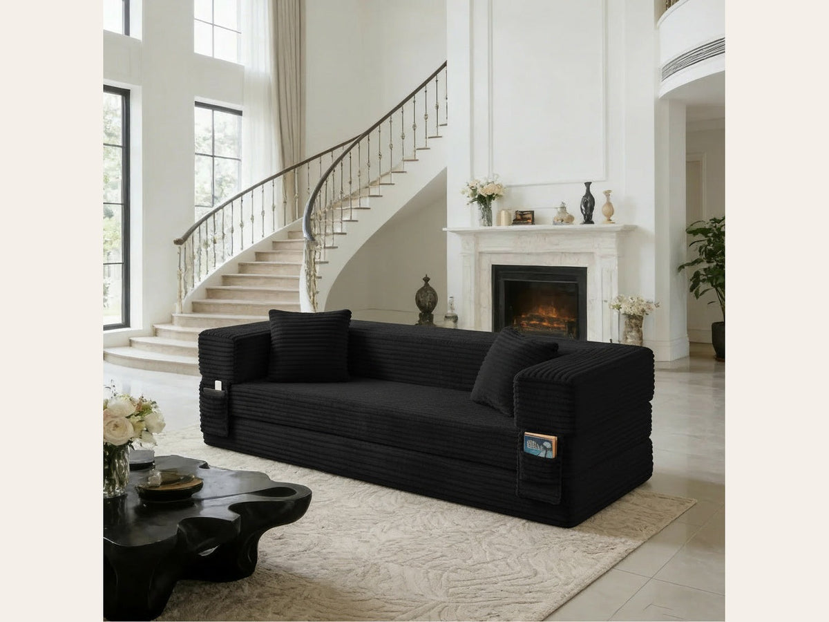 Pouf lit pliant en velours côtelé, coloris noir, en situation, cheminée