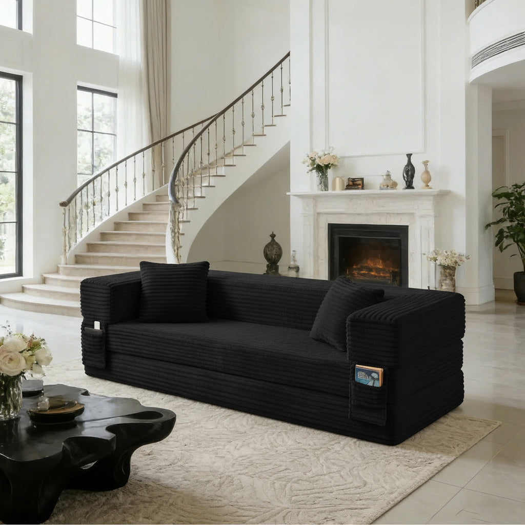 Pouf lit pliant en velours côtelé, coloris noir, en situation, cheminée