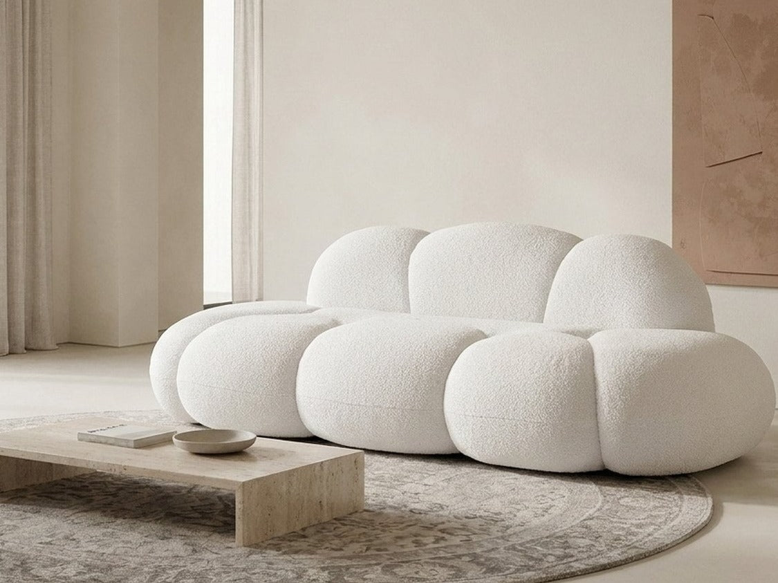 Canapé nuage 3 places sans accoudoir, tissu bouclé blanc écru, dans un salon clair près d'une table basse