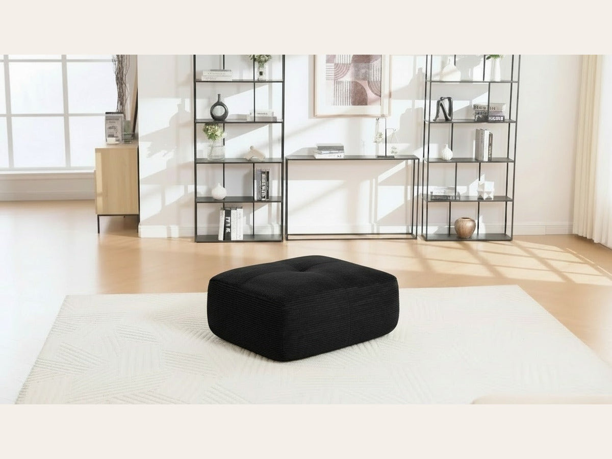 Pouf velours côtelé noir, de trois quarts dans un salon