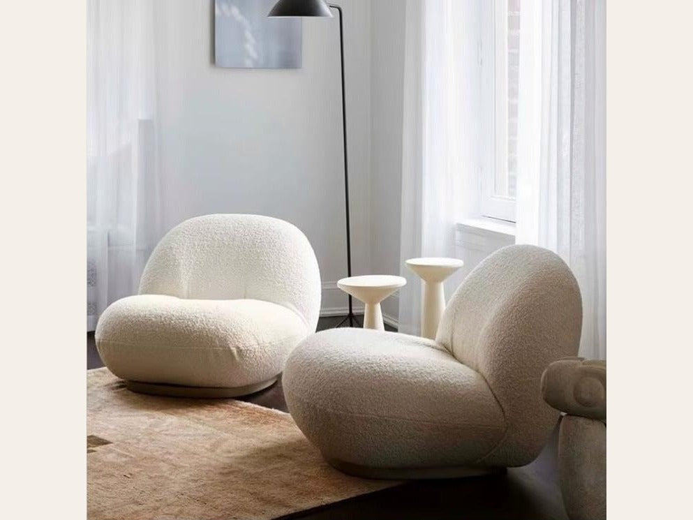 Fauteuil nuage pivotant 360 en tissu bouclette blanc écru, présenté en duo dans un salon, avec lampadaire et tables d'appoint