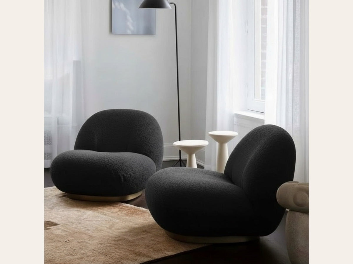 Fauteuil nuage pivotant 360 en tissu bouclette noir charbon, présenté en duo dans un salon, avec lampadaire et tables d'appoint