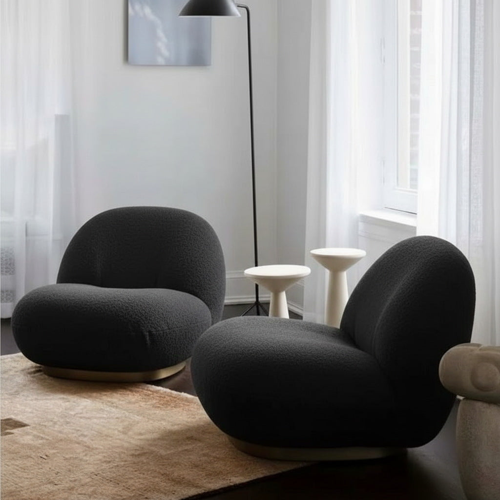 Fauteuil nuage pivotant 360 en tissu bouclette noir charbon, présenté en duo dans un salon, avec lampadaire et tables d'appoint